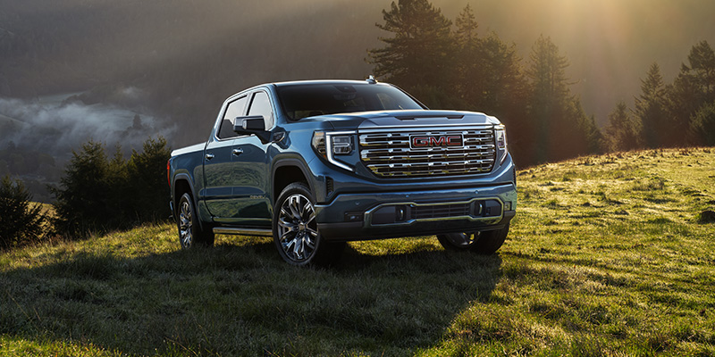 GMC Sierra 1500 pickup truck on hillside at sunset